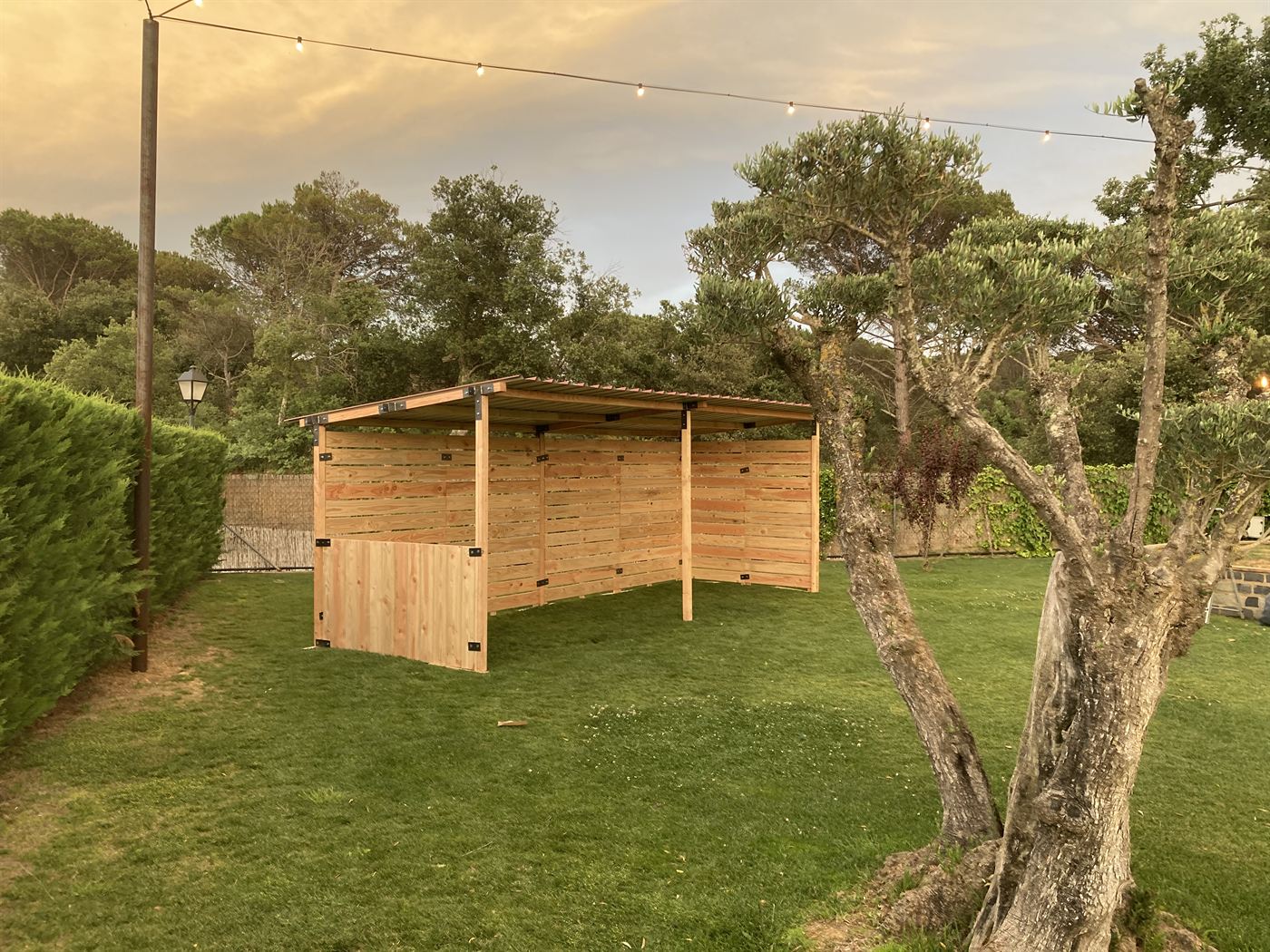 Estand de fusta muntat en un jardí, amb els panells i el sostre a punt per a un esdeveniment
